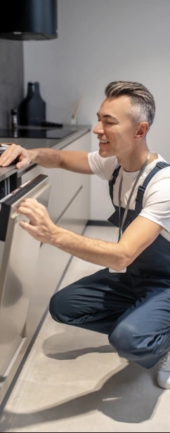 A man repairing a dishwasher in a kitchen.